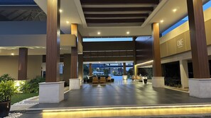 A spacious indoor area with a central seating area, large pillars, and a coffee shop named 'ONE'. -  XANADU CASA DE LA PLAYA (Puerto Plata)