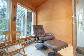 Ein Zimmer mit einem Holzschaukelstuhl, einem Ledersessel und einer Tür mit Messinggriffen.