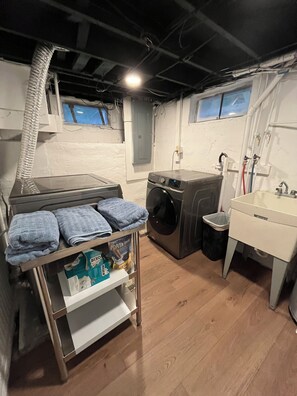 A laundry room with a washing machine, a sink, and a drying rack with folded towels. - 3-bedroom house in peaceful, rural hideaway (Schenectady)
