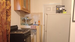 A compact kitchen with a stove, oven, and refrigerator. A dish rack and a bottle of dish soap are visible on the counter. - COLDEST 1-bedroom apartment with AC in serene Montego Bay (Montego Bay)