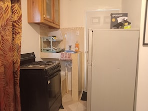 A compact kitchen with a stove, oven, and refrigerator. A dish rack and a bottle of dish soap are visible on the counter. - COLDEST 1-bedroom apartment with AC in serene Montego Bay (Montego Bay)