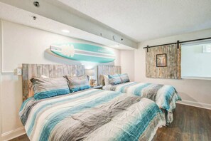 Ein Schlafzimmer mit zwei Betten, einer Surfbrettern als Dekoration und einem Fenster mit Vorhängen.