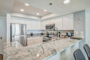 Une cuisine moderne avec des meubles blancs, des appareils en acier inoxydable et un plan de travail en marbre.