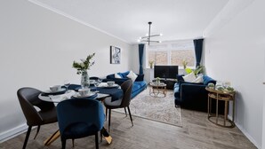 A modern living room with a dining area, a sofa set, a TV, and a dining table with chairs. - 2 Bed 1 Bath Apt in Fulham in Zone 2 (London)