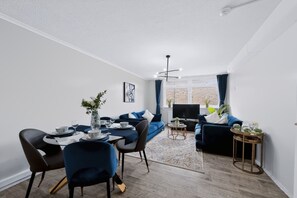 A modern living room with a dining area, a sofa set, a TV, and a dining table with chairs. - 2 Bed 1 Bath Apt in Fulham in Zone 2 (London)