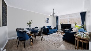 A modern living room with a dining area, a sofa set, a TV, and a large window. - 2 Bed 1 Bath Apt in Fulham in Zone 2 (London)