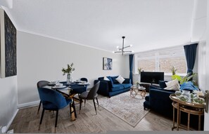 A modern living room with a dining area, a sofa set, a TV, and a large window. - 2 Bed 1 Bath Apt in Fulham in Zone 2 (London)