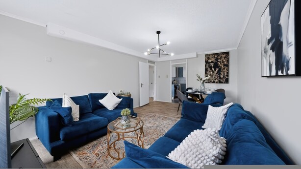 A modern living room with a blue sofa set, a coffee table, and a dining area in the background. - 2 Bed 1 Bath Apt in Fulham in Zone 2 (London)