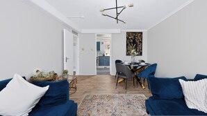 A modern living room with a dining area, a kitchen in the background, and a hallway leading to an open space. - 2 Bed 1 Bath Apt in Fulham in Zone 2 (London)