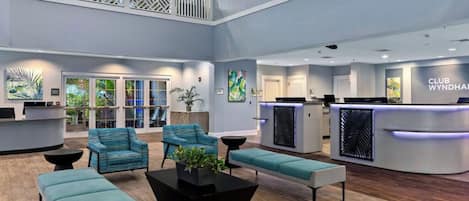 A spacious lobby with a reception desk, seating area, and a balcony.