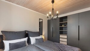 Ein Schlafzimmer mit Bett, Kleiderschrank, Spiegel und einer Kronleuchter.