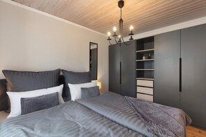 Un dormitorio con cama, armario, espejo y candelabro.