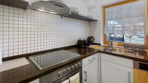 Eine moderne Küche mit Gasherd, Backofen, Kaffeemaschine und einem Fenster mit Aussicht.