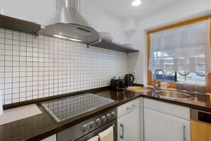 Una cocina moderna con estufa a gas, horno empotrado, cafetera y ventana con vistas.