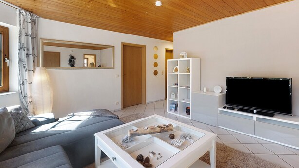 Ein modernes Wohnzimmer mit Sofa, Couchtisch, Fernseher und Holzboden.