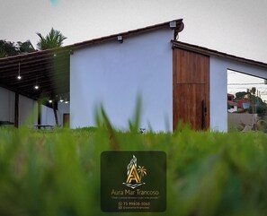 Ein modernes Gebäude mit weißer Fassade, einer Holztür und einem überdachten Außenbereich mit Tisch und Stühlen.