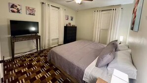 Ein Schlafzimmer mit Bett, Fernseher, Deckenventilator und Kommode.