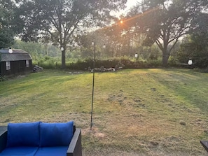 A backyard with a lawn, a wooden structure, and a blue outdoor seating area. - Crowders Cozy Retreat (Gastonia)