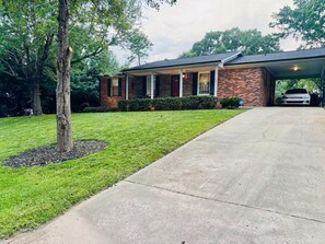 A residential house with a covered garage, a paved driveway, and a well-maintained lawn.