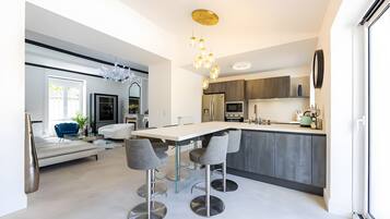 Een moderne keuken met een centraal eiland, barstoelen en een zithoek met een bank en stoelen.
