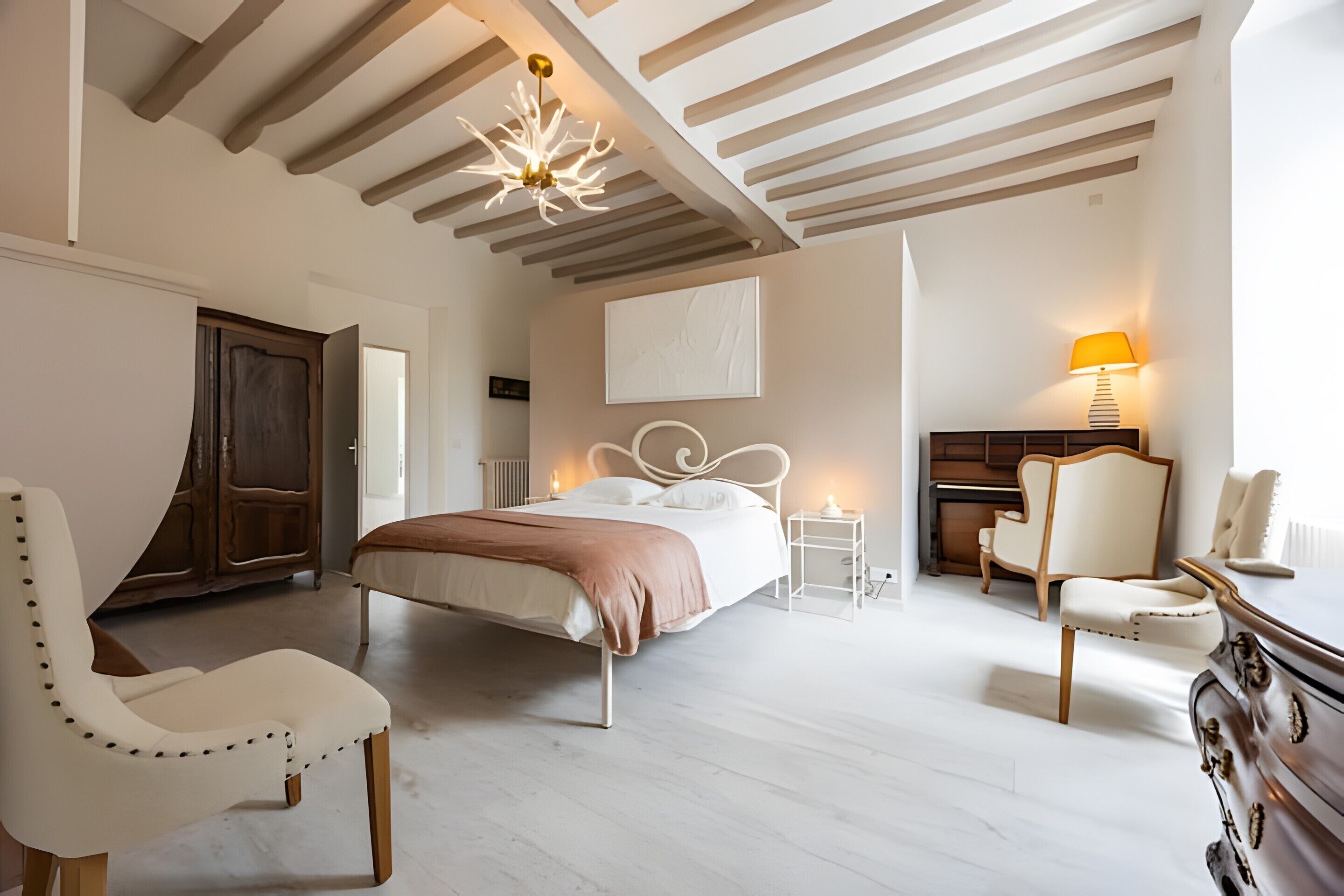 Een slaapkamer met een bed, twee stoelen, een kaptafel, een nachtkastje, een lamp en een plafondarmatuur.
