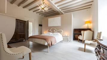 Een slaapkamer met een bed, twee stoelen, een kaptafel, een nachtkastje, een lamp en een plafondarmatuur.