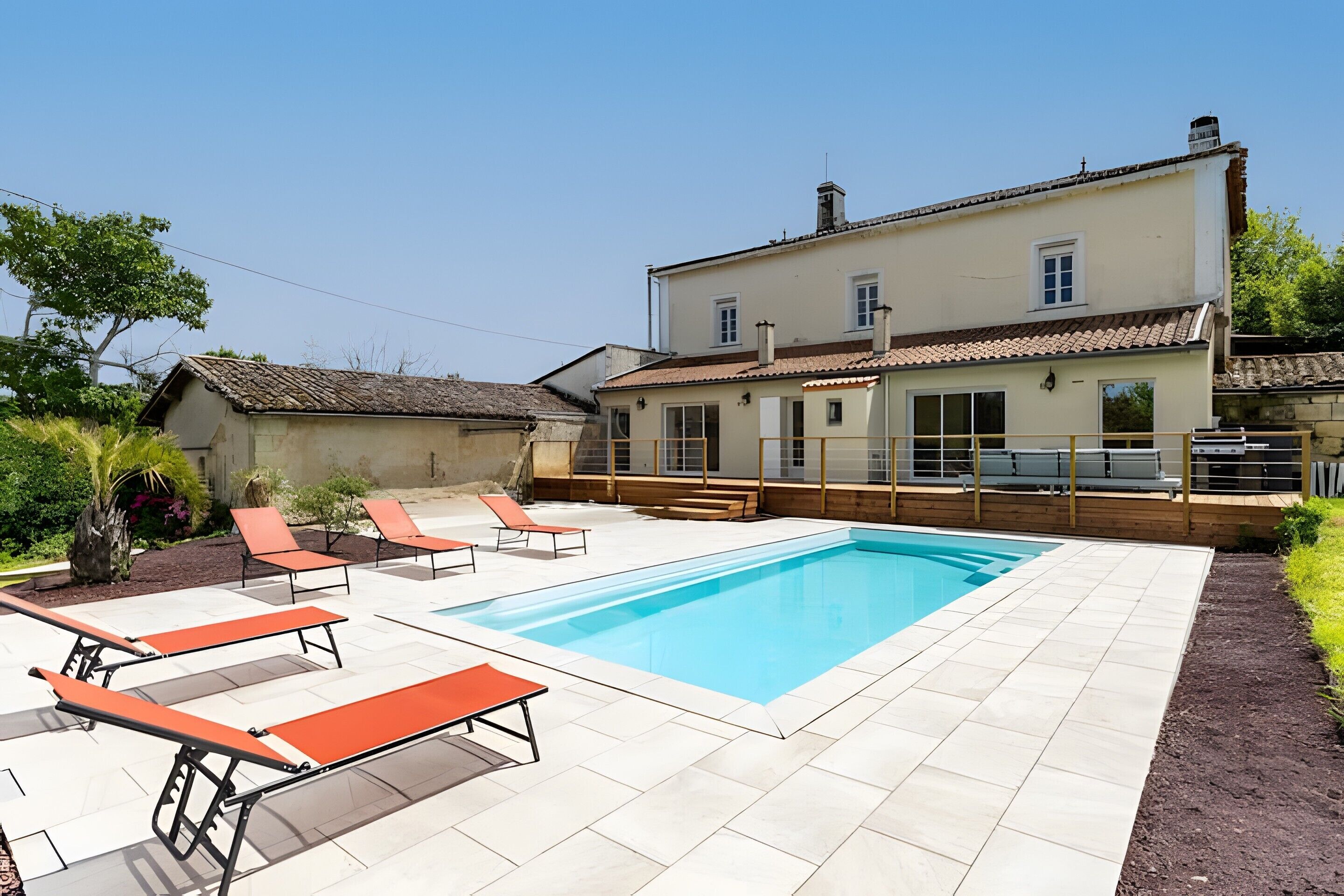 Een woonhuis met een zwembad, terras en een groot huis.
