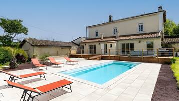 Een woonhuis met een zwembad, terras en een groot huis.