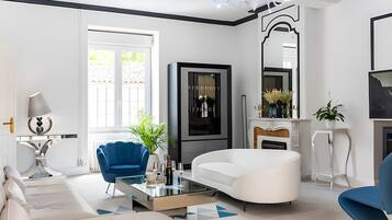 A modern living room with a white sofa, blue armchair, and a glass coffee table.