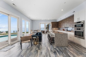 A modern kitchen with a large island, built-in appliances, and a view of a pool. - Azure Bay Retreat (Ocean City)