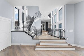 Ein modernes Interieur mit einer zentralen Treppe, großen Fenstern und einem Holzboden.