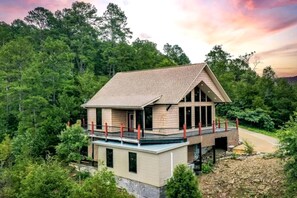 Ein zweistöckiges Haus mit Balkon, umgeben von dichtem Wald.