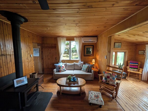 A cozy cabin interior with a sofa, a round wooden table, and a chair.