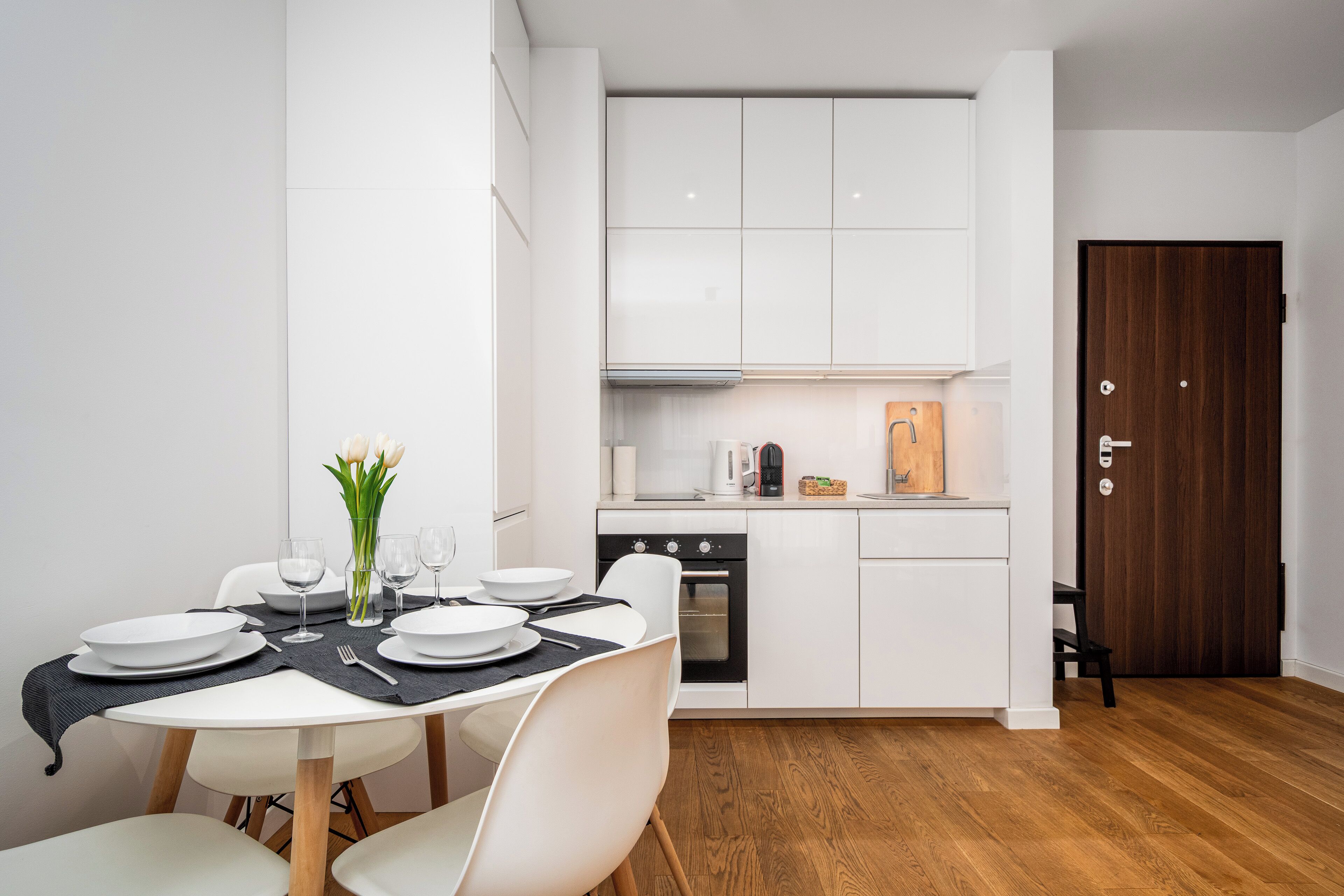 A compact kitchen with white cabinets, a built-in oven, and a coffee maker.