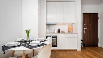 Una cocina compacta con armarios blancos, horno empotrado y cafetera.