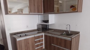 A kitchen with wooden cabinets, a microwave, a sink, and a countertop. - Landscape Apartment in Fortaleza Gold (Fortaleza)