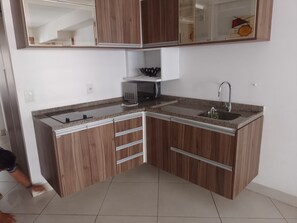 A kitchen with wooden cabinets, a microwave, a sink, and a countertop. - Landscape Apartment in Fortaleza Gold (Fortaleza)