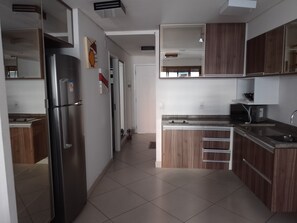 A modern kitchen with a stainless steel refrigerator, wooden cabinets, a microwave, and a sink. - Landscape Apartment at Fortaleza Gold (Fortaleza)