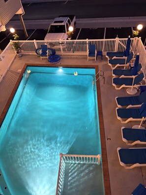 Ein Swimmingpool mit Liegestühlen und einem weißen Zaun.
