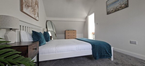Une chambre à coucher avec un lit, une table de chevet, une lampe et une fenêtre.