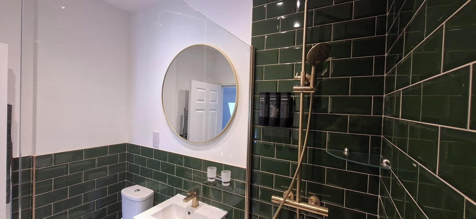 A bathroom with a sink, mirror, and shower.