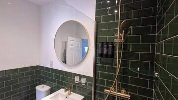 A bathroom with a sink, mirror, and shower.