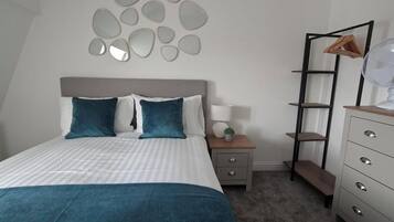 A bedroom with a bed, bedside table, lamp, and a dresser with drawers.
