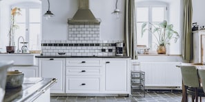 Een keuken met witte kasten, een betegelde achterwand en een koffiezetapparaat.