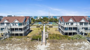 A beachfront property with two-story buildings, a central pathway, and a view of the ocean. - Top-Floor Ocean Views | Pool + Beach Access (Emerald Isle)