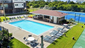 Ein Swimmingpool mit Liegestühlen und einem überdachten Sitzbereich.