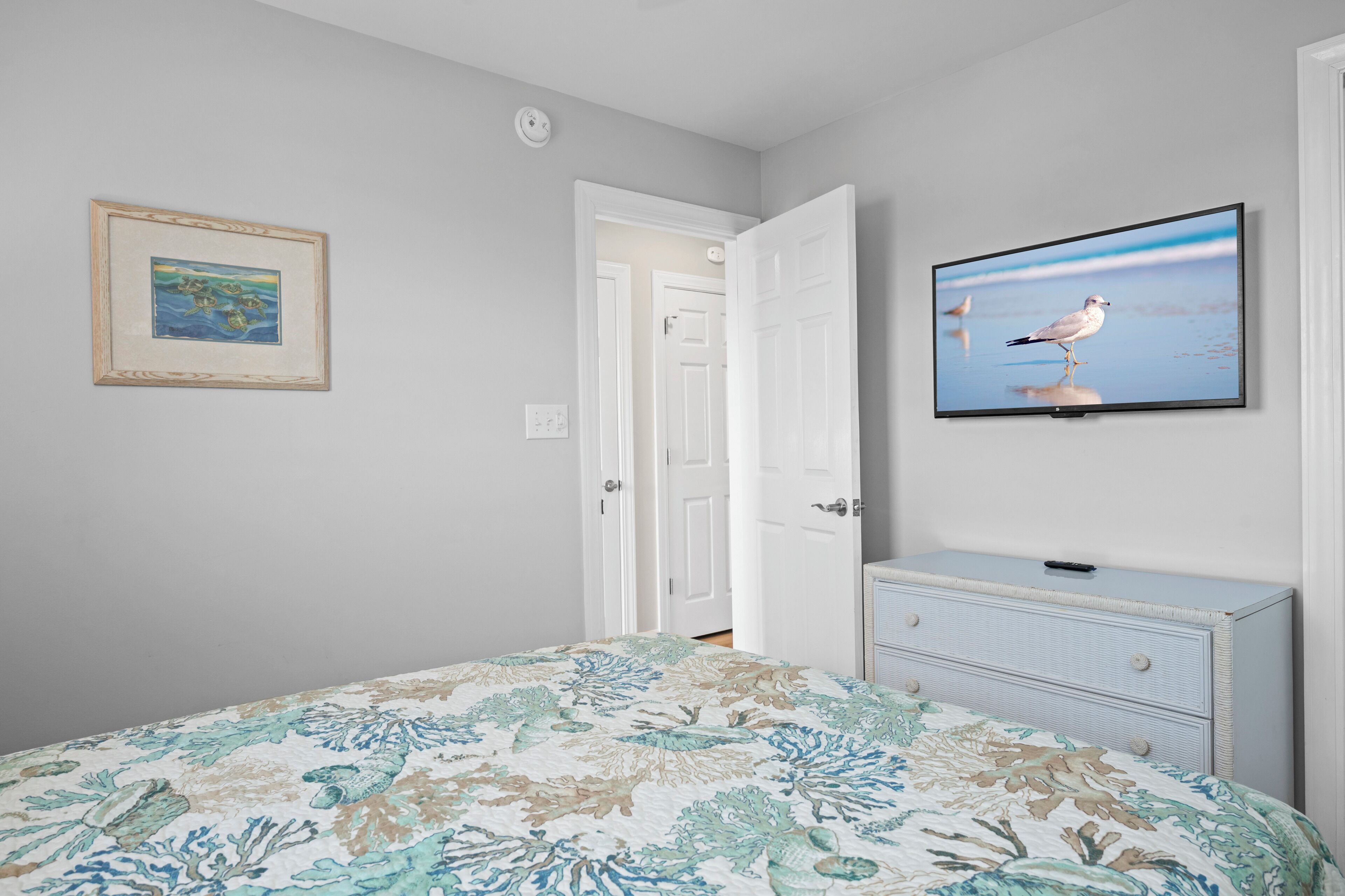A bedroom with a bed, a dresser, a television, and a door.