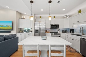 A modern kitchen with white cabinetry, stainless steel appliances, and a marble island. - Top-Floor Ocean Views | Pool + Beach Access (Emerald Isle)