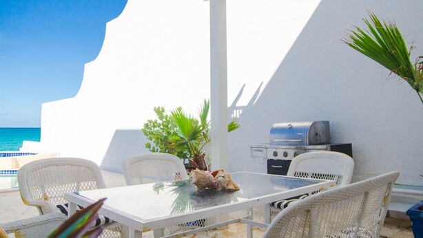 Eine Terrasse mit Tisch und Stühlen, einem Grill und Blick auf das Meer.