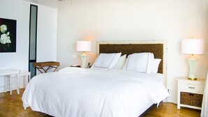 Ein Hotelzimmer mit einem Bett, zwei Nachttischen mit Lampen, einem Deckenventilator, einem Bild an der Wand und einem kleinen Tisch mit einem Korb.